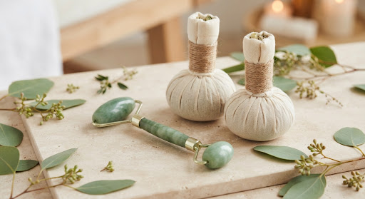 Herbal compresses and jade massage tools with fresh botanical ingredients